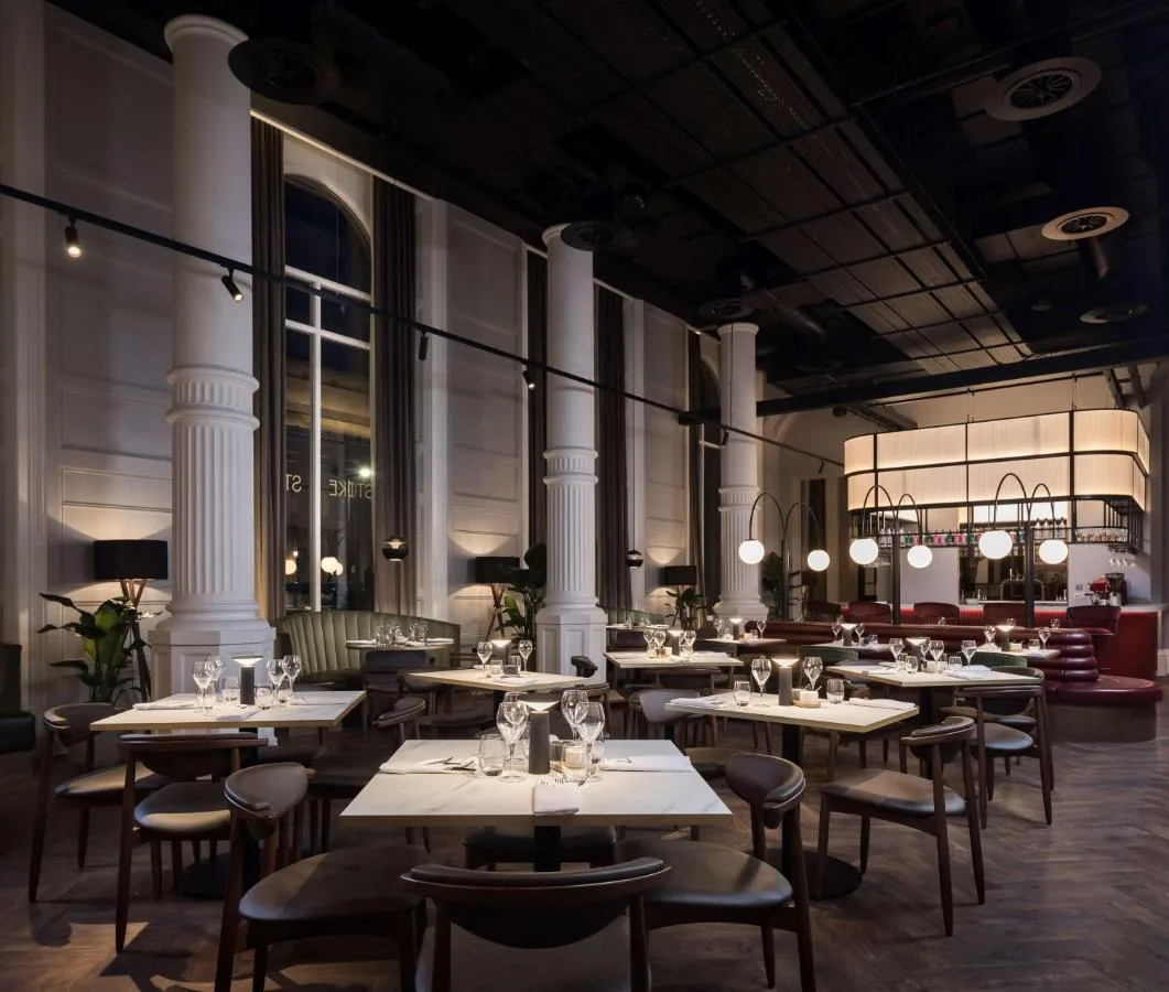 a restaurant with white tables and chairs and large windows at Radisson RED Hotel, Liverpool in Liverpool